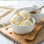 Creamy cottage cheese ice cream in a bowl with maple drizzle and wooden spoon – healthy homemade dessert