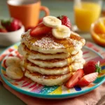 Fluffy cottage cheese pancakes stacked on a plate with fresh fruit, perfect for kids